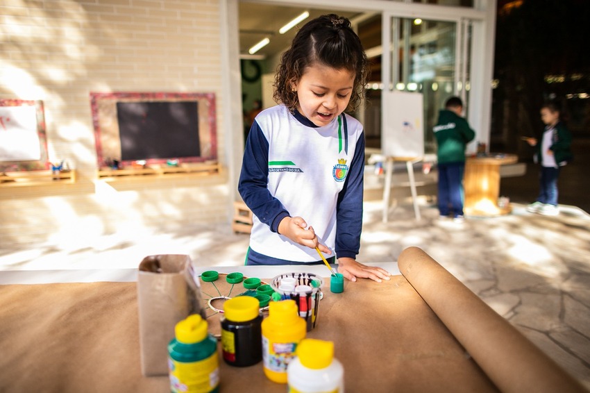 Criança brincando de pintar com tinta guache