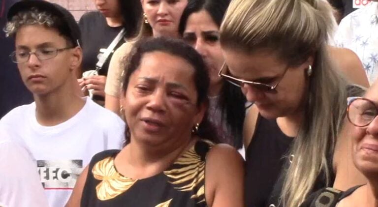 Muito emocionada, mãe é amparada durante enterro da filha.